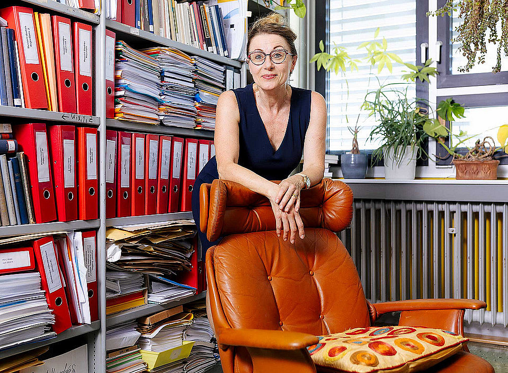 Frau steht hinter einem Sessel 