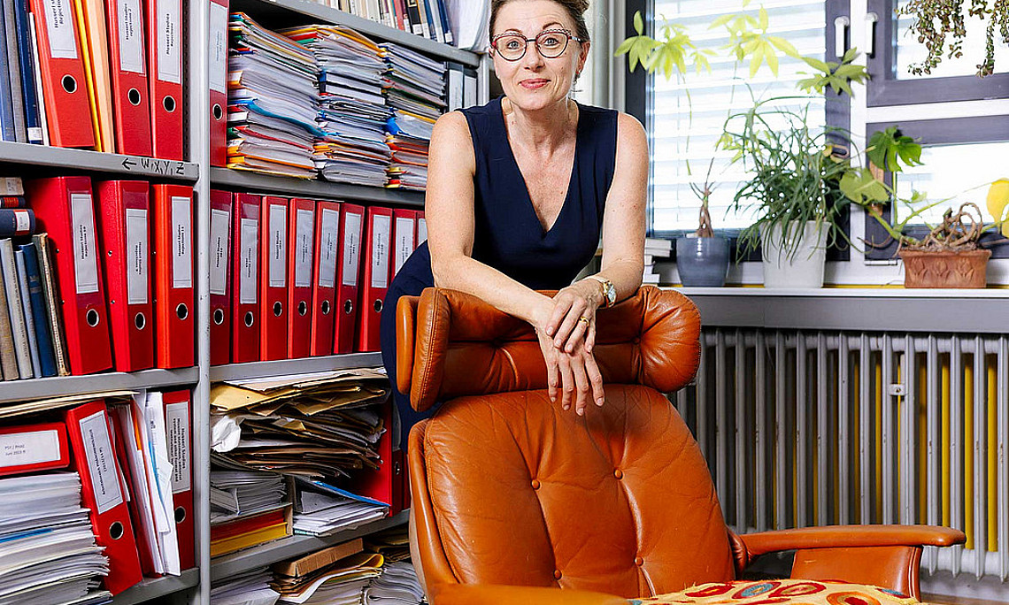 Frau steht hinter einem Sessel