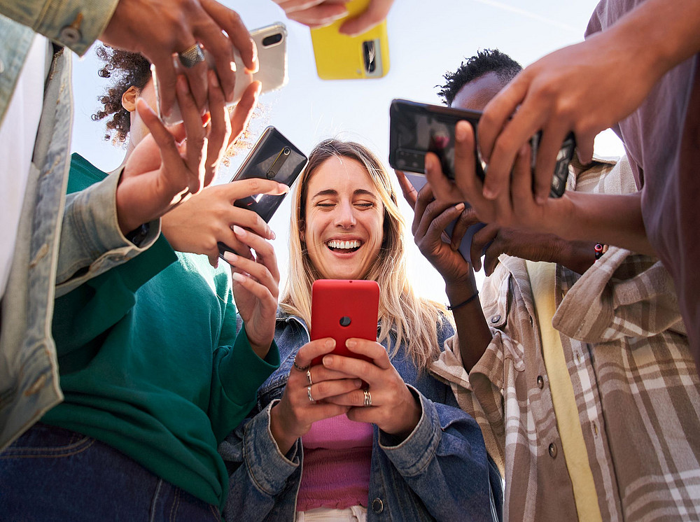 Personen blicken lächelnd auf ihr Smartphone ©CarlosBarquero - stock.adobe.com