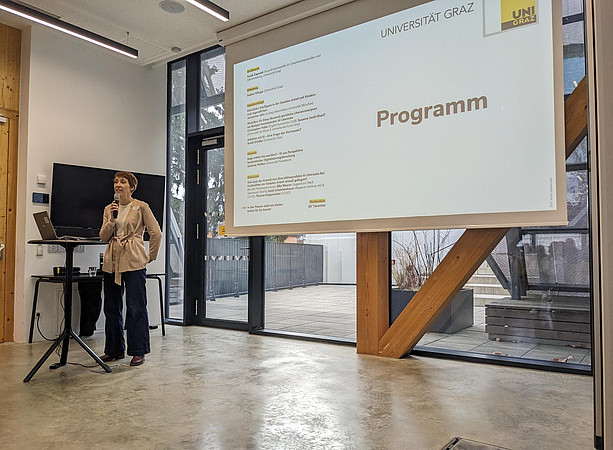 eine Frau steht vor einer Leinwand und spricht in ein Mikrofon ©Uni Graz/Schmieder