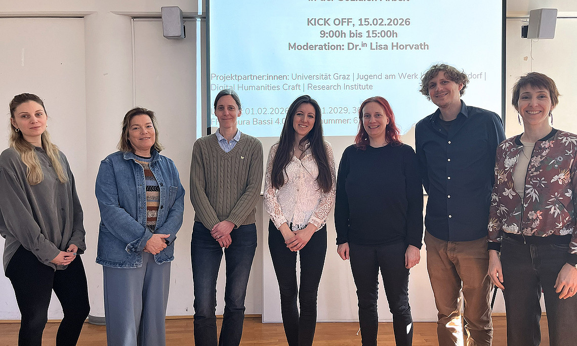Sechs Frauen und ein Mann stehen in einer Reihe vor einer Leinwand, auf der Infos zum Projekt SocialAI eingeblendet sind