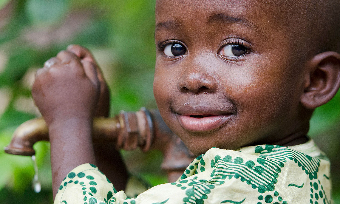 kleiner afrikanischer Bub umfasst einen Wasserhahn