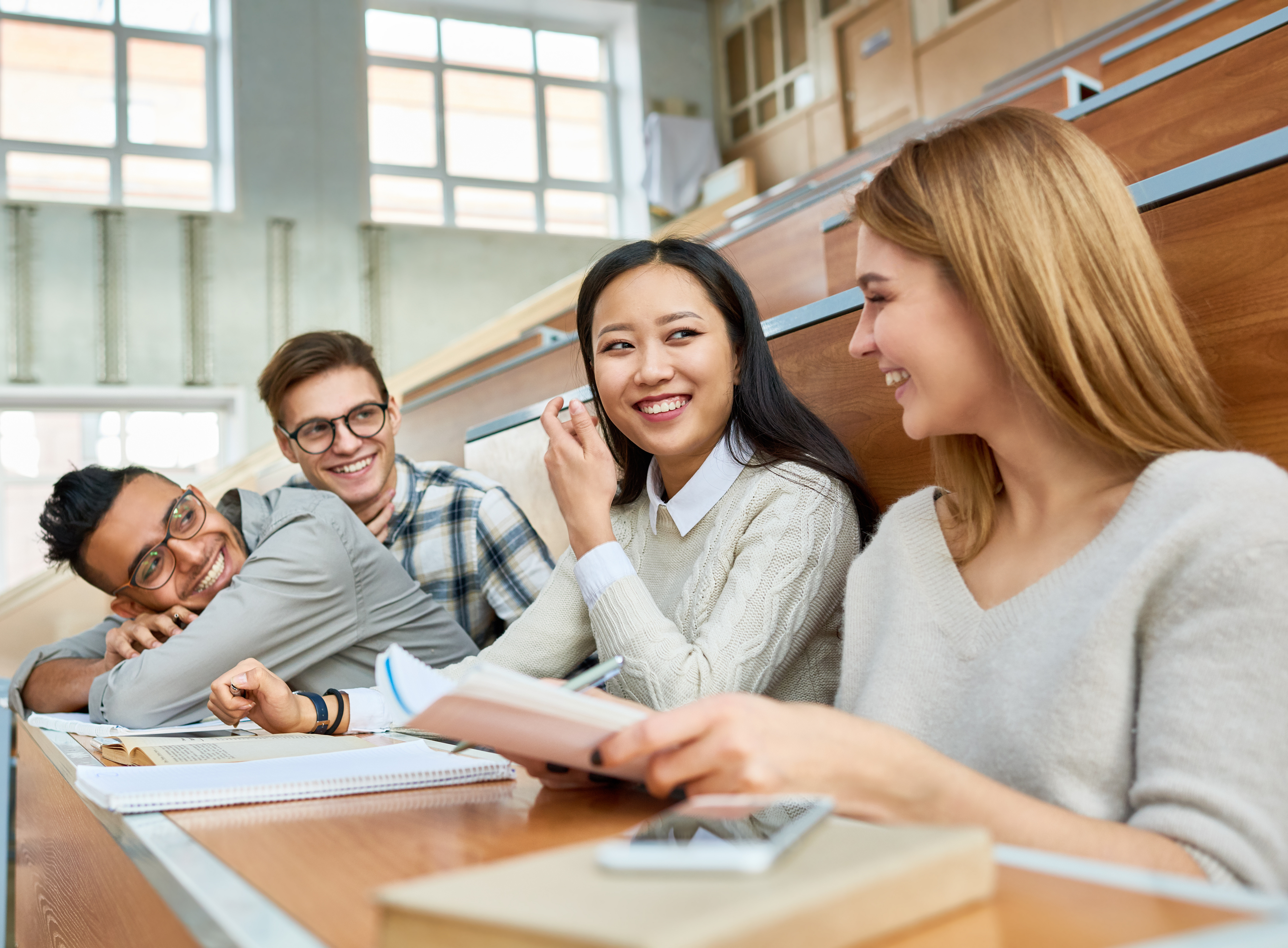 Multi-ethnic group of cheerful students sitting at desks in lecture hall of modern college and laughing ©By Seventyfour; stock.adobe.com