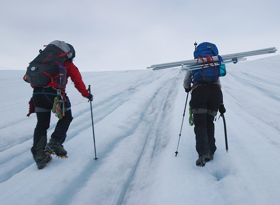 Two people with rucksacks and alpine equipment walk up a glacier ©Wally and Fauland