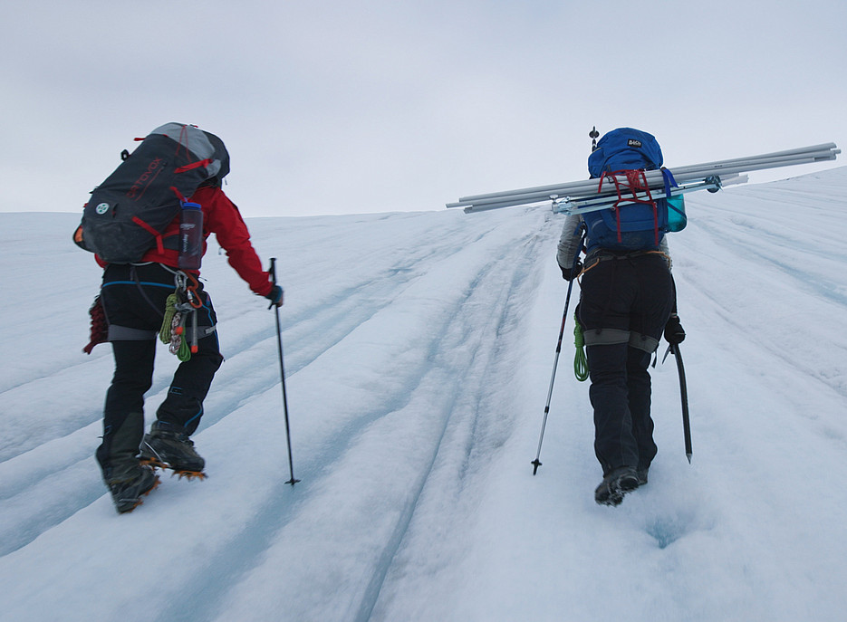 Zwei Personen mit Rucksack und Alpinausrüstung gehen einen Gletscher hinauf ©Wally and Fauland