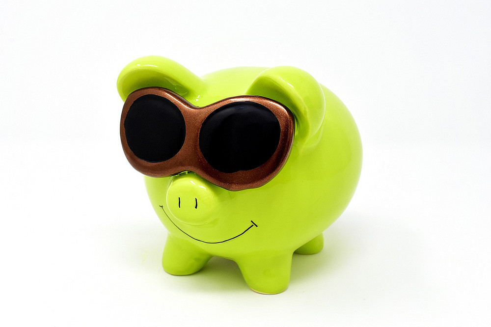 grünes Sparschwein mit Sonnenbrille 