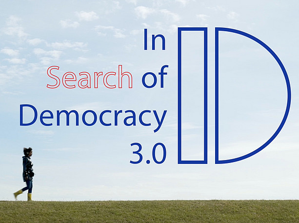 UniVibes, das Fest der Uni Graz 2025, Lucas de Man ©Lucas de Man A person walks across a meadow, above the lettering In Search of Democracy 3.0 ©Lucas de Man