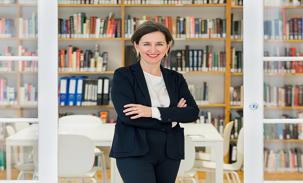 Barbara Stelzl-Marx vor einer Bücherwand, stehend, die Arme verschränkt