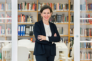 Barbara Stelzl-Marx, standing in front of a wall of books, arms folded