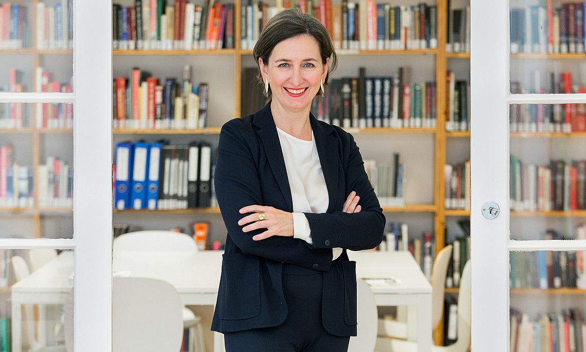 Barbara Stelzl-Marx, standing in front of a wall of books, arms folded