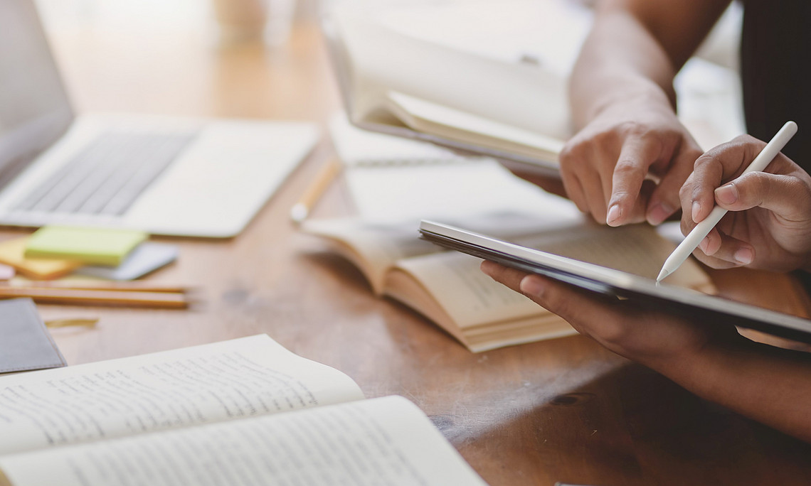 Zwei Personen mit Laptop, Bücher, Tablet