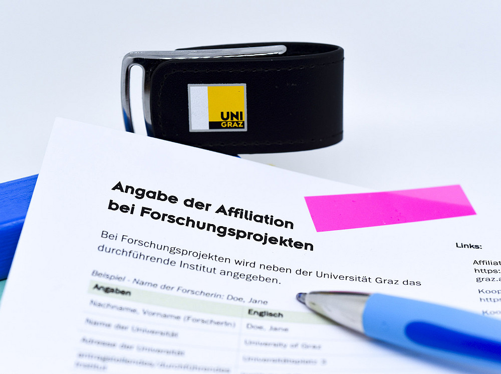 Ein Blatt Papier mit Stift, Post-it und Angaben zur Affiliation. ©Uni Graz/Schwarz