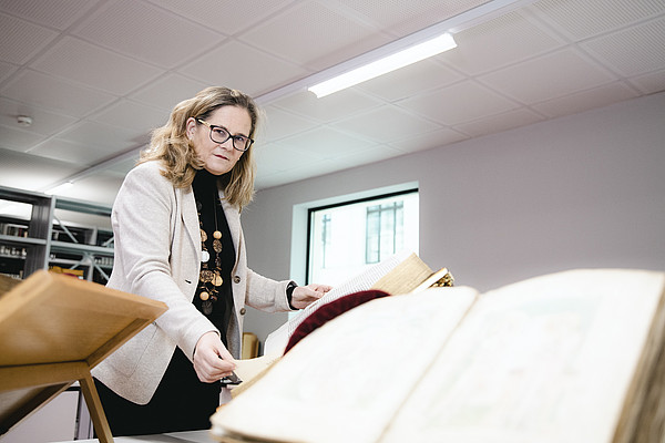 Pamela Stückler, die Leiterin der UB Graz, ist Expertin für alte Schriften. Beim Schmökern in der Stratter-Bibel sucht sie nach dem Weihnachtsevangelium. Fotos: Uni Graz/Tzivanopoulos 