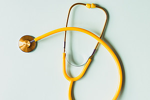 Gelbes Stethoskop auf hellblauem Hintergrund