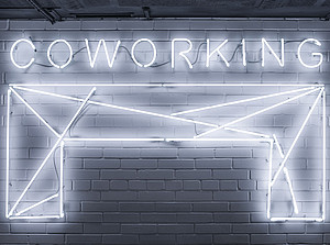 Illuminated tubes on a wall draw a desk and the lettering "COWORKING" ©Vladimir Proskurovskiy