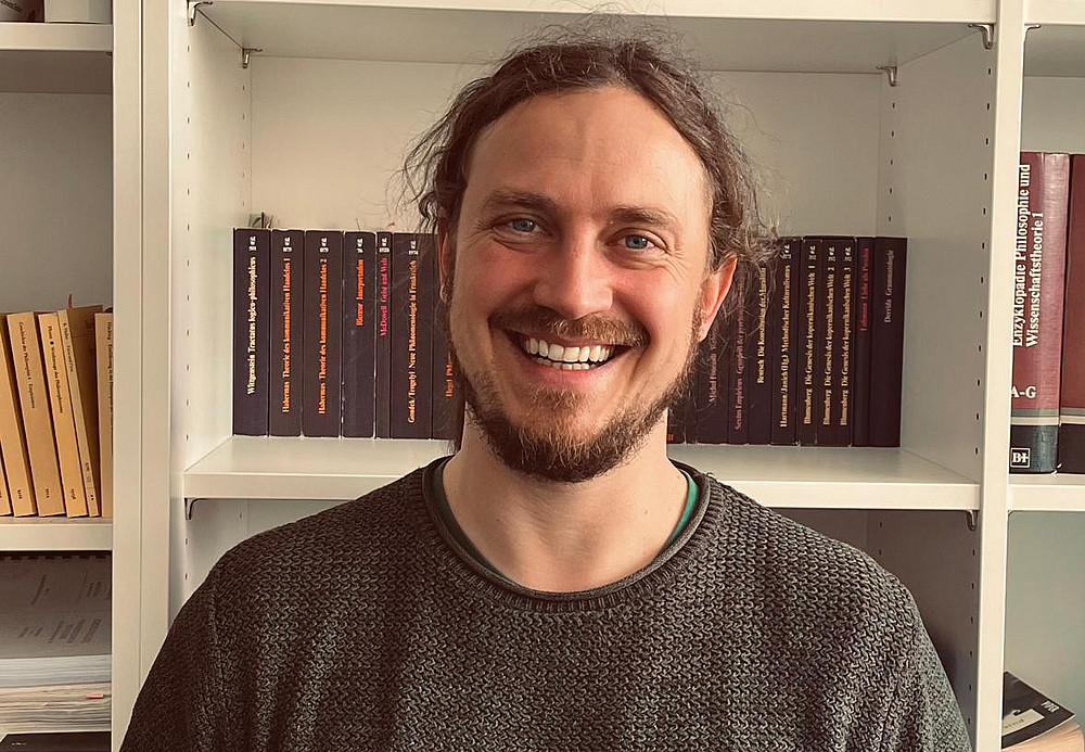 Bernhard Gaißler, one of several doctoral students, in front of a bookshelf ©Michael Wallner
