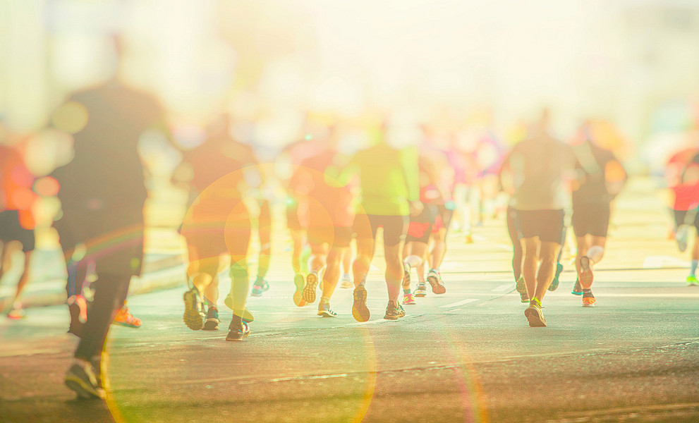 Menschen in Sportbekleidung laufen auf einer Straße, verschwommen, von hinten