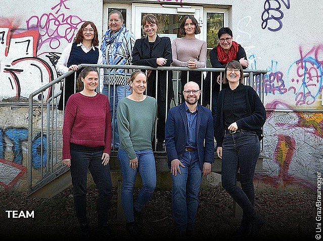 das 9-köpfige Team des Fachbereichs Erwachsenen- und Weiterbildung der Uni Graz vor einer bunten Graffiti-Wand 