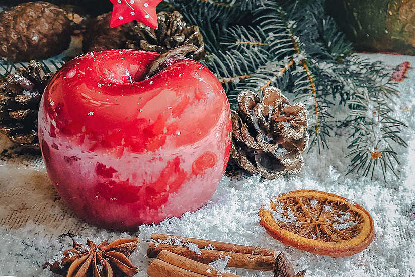 Weihnachtsdeko: roter Apfel, Sternanis, Zimtstangen, Föhrenzapfen, getrocknete Orangenscheibe, Tannenzweig, Schnee. Foto: pixabay