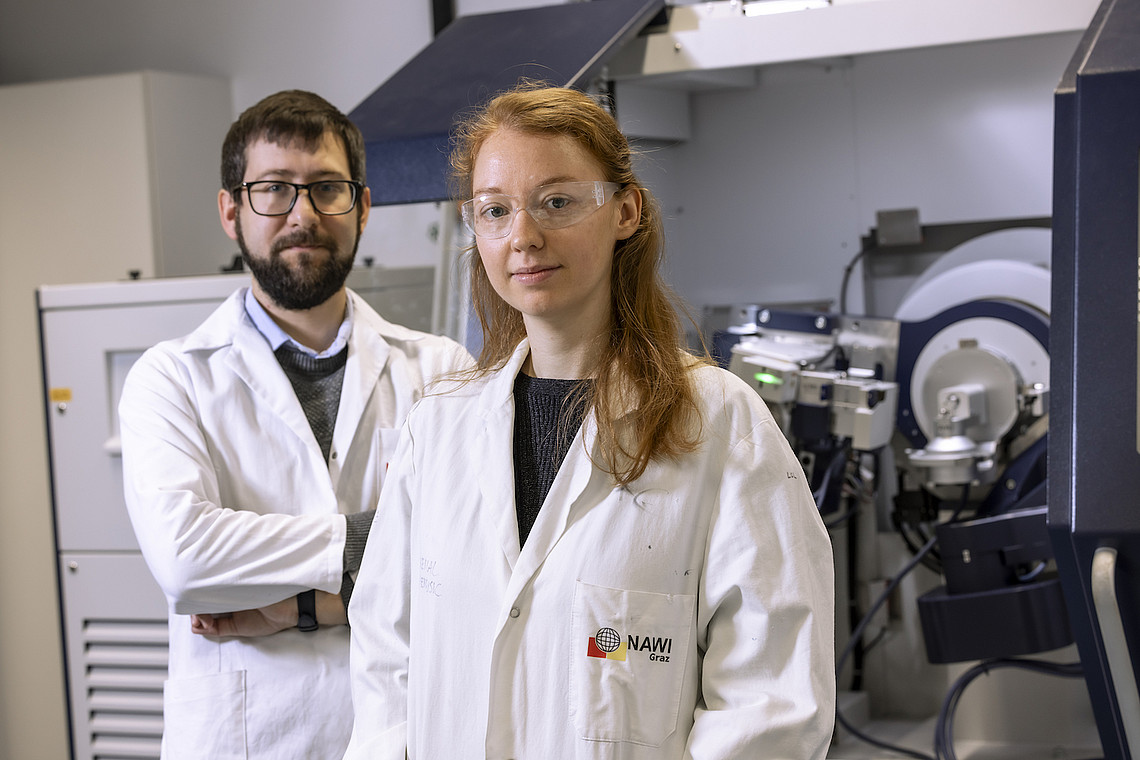 Zwei Personen in Labormänteln stehen vor einer Maschine und symbolisieren die Studien der NAWI Graz