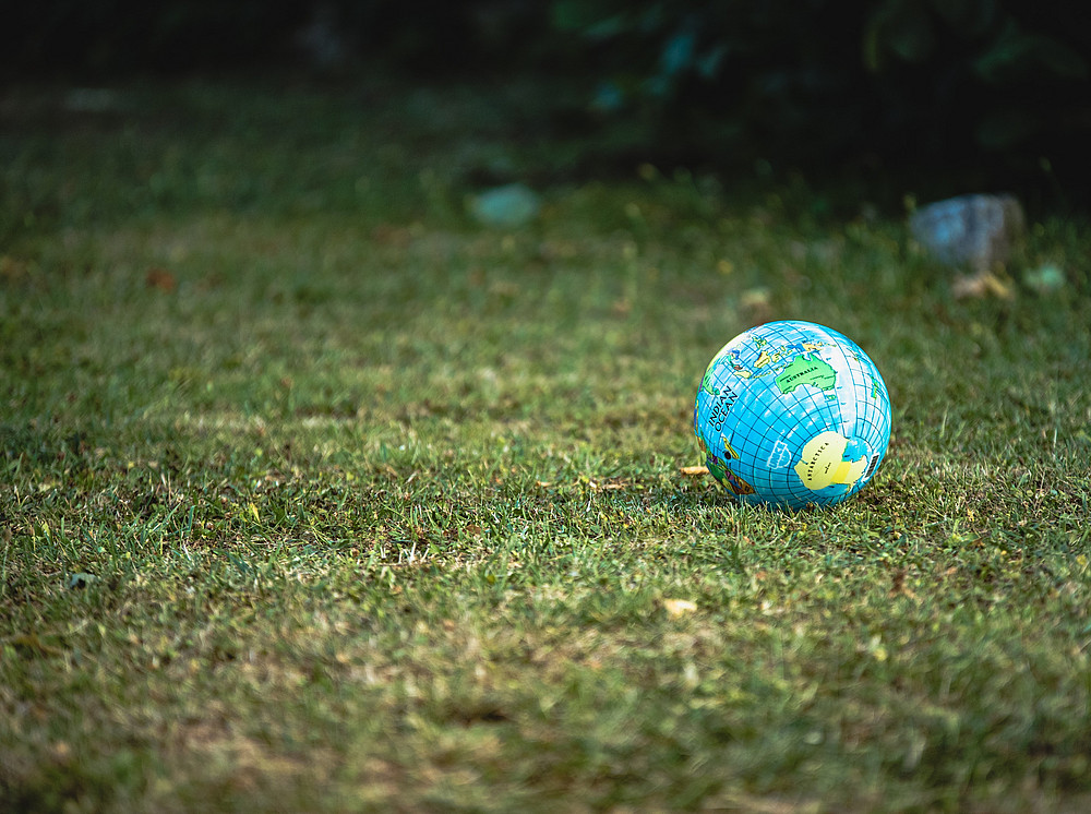Eine Weltkugel liegt in der Wiese ©Photo by Guillaume de Germain on Unsplash
