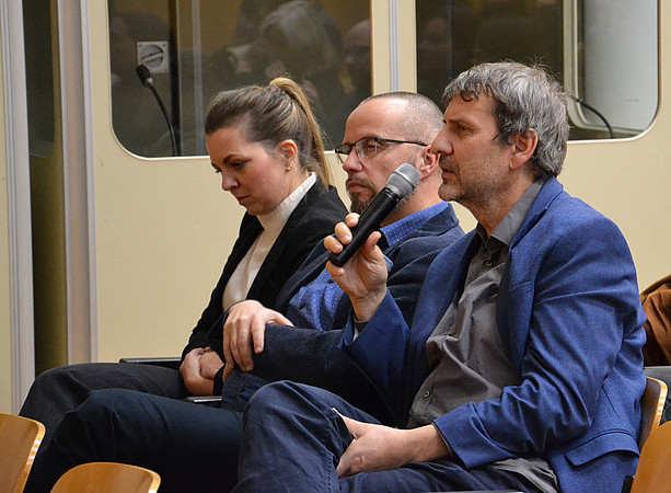 eine Frau und zwei Männer sitzen in einem Hörsaal, einer der Männer spricht in ein Mikrofon ©Uni Graz/Braunegger