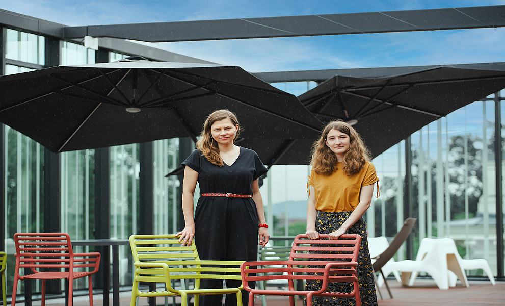 Zwei Frauen stehen auf der Terrasse der Uni-Bibliothek Graz unter blauem Himmel