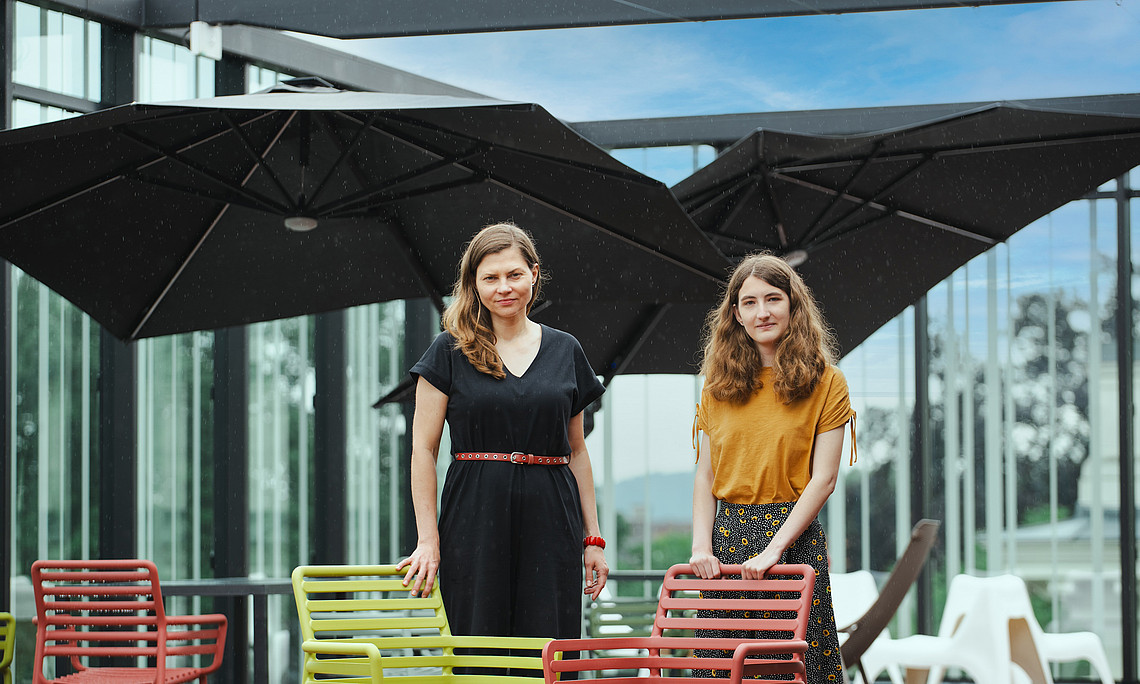 Zwei Frauen stehen auf der Terrasse der Uni-Bibliothek Graz unter blauem Himmel