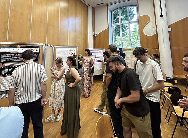 Studierende, die sich eine Plakatausstellung ansehen 