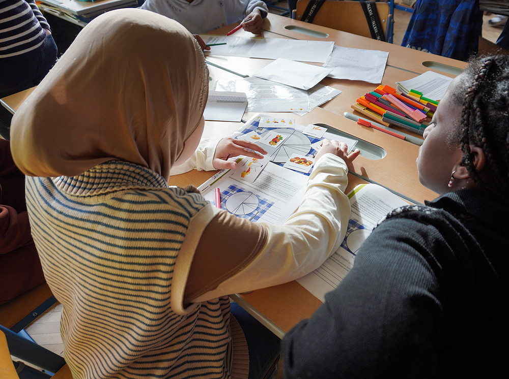 Schüler:innen betrachten ein Lehrbuch 