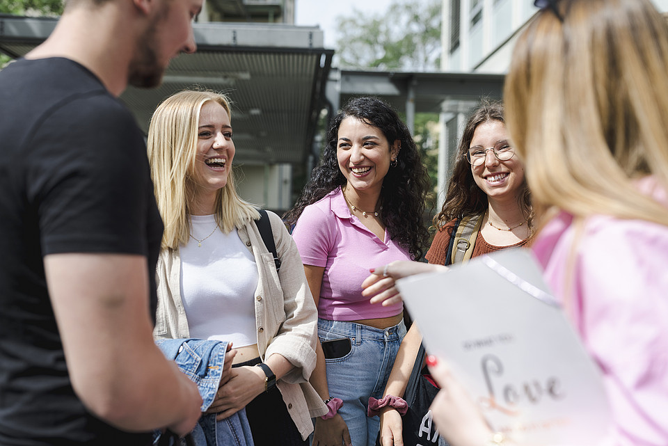 Studierende stehen gemeinsam im Freien und unterhalten sich