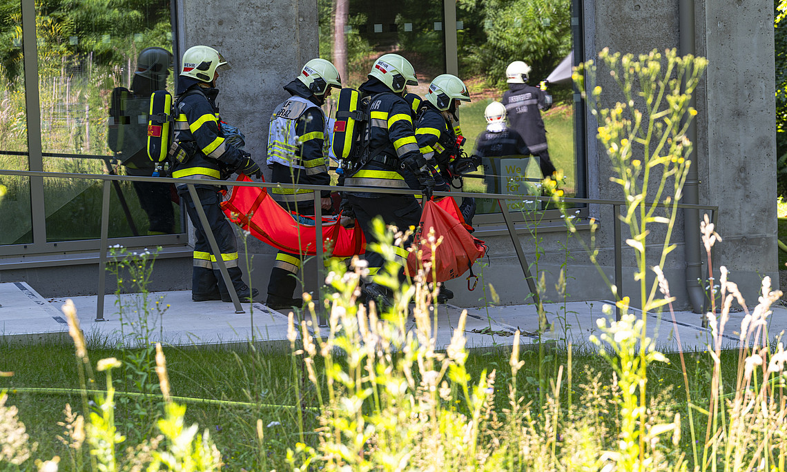 Leute in Feuerwehrbekleidung tragen eine verletzte Person