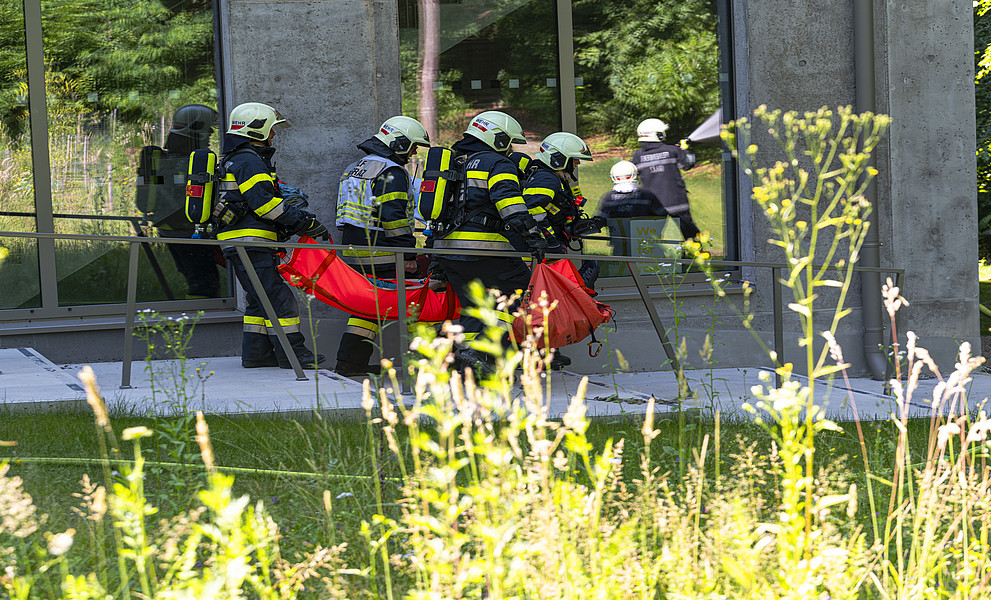 Leute in Feuerwehrbekleidung tragen eine verletzte Person