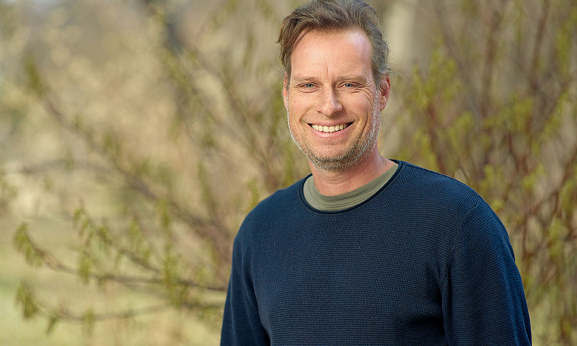 Biologe Gernot Kunz vor einem Strauch im Botanischen Garten der Universität Graz