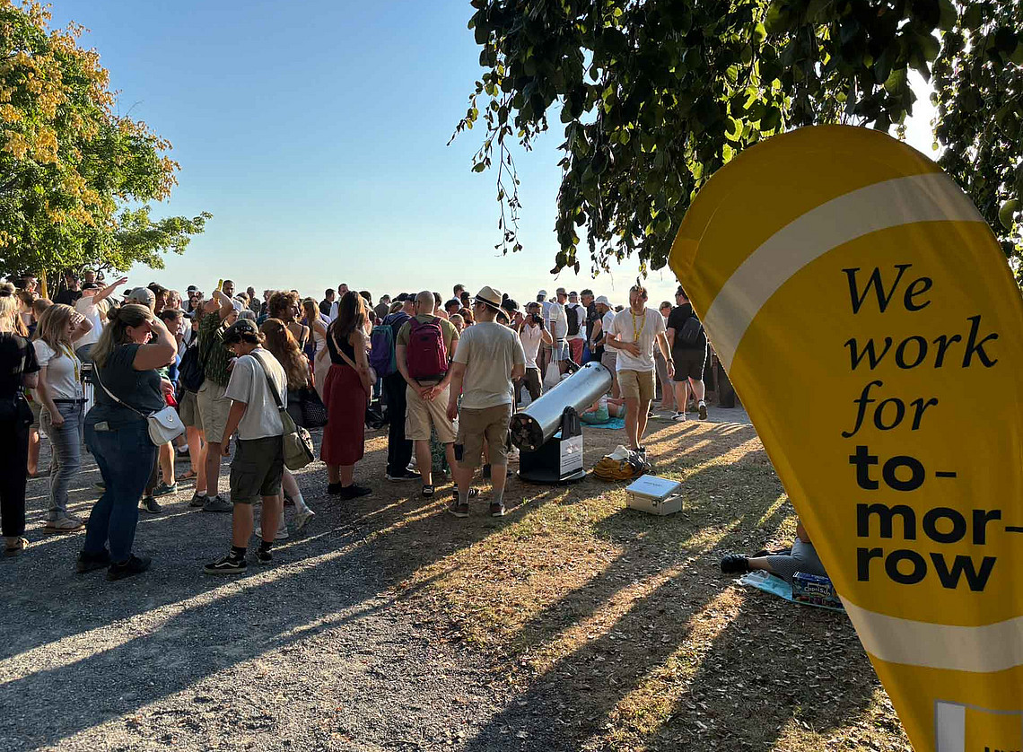 Menschen auf dem Schloßberg, auf einem Bech Flag ist We work for tomorrow zu lesen