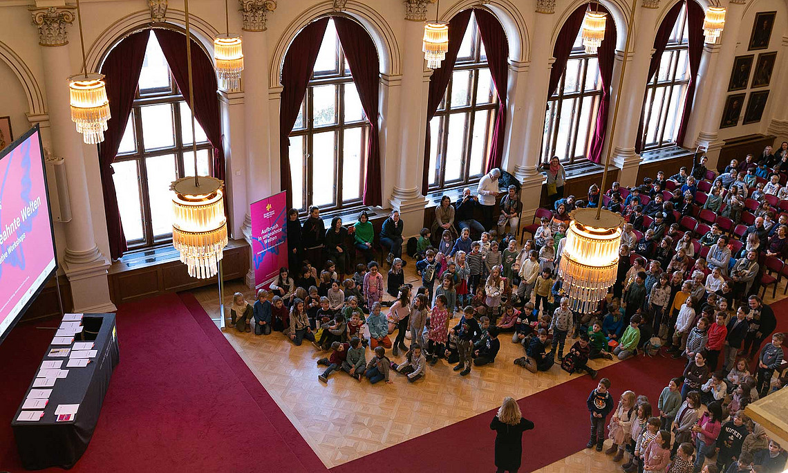 Viele Kinder in der Aula der Uni Graz, fotografiert von oben, von der Galerie