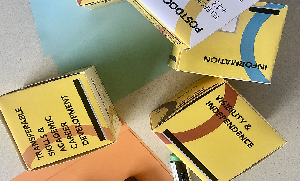 Stifte und Würfel auf grauem Grund