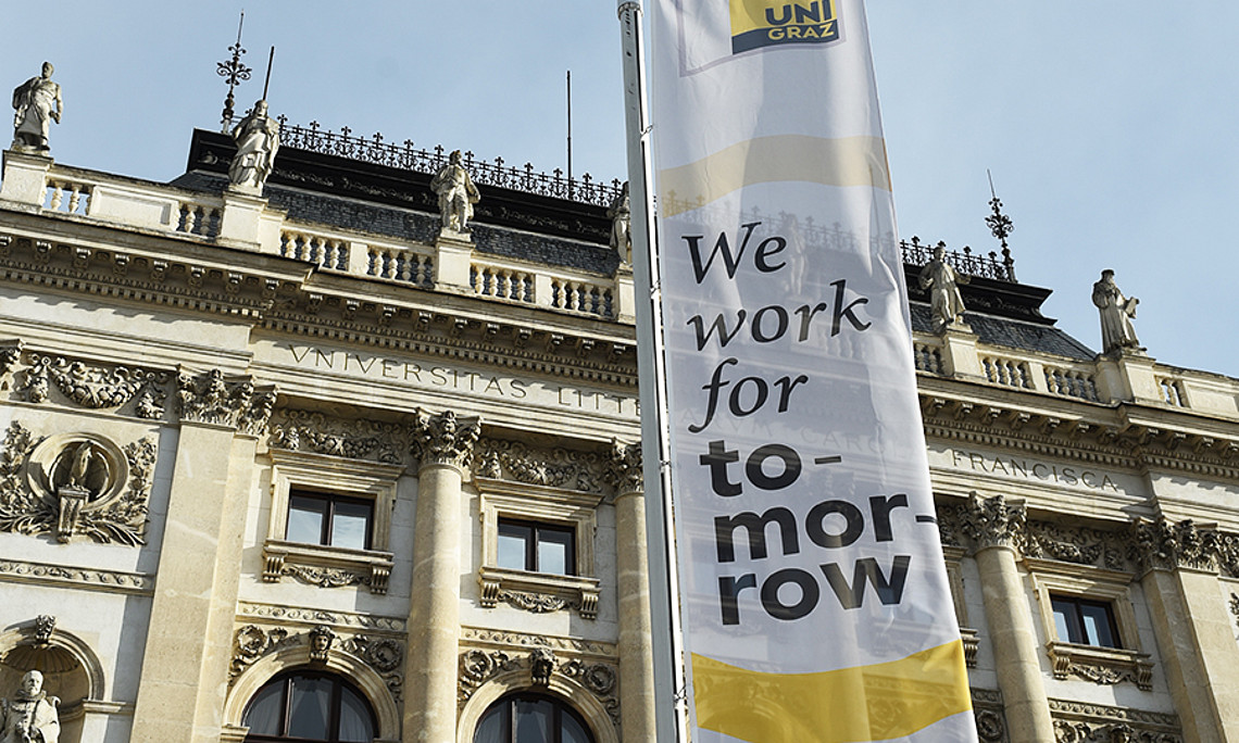 Hauptgebäude der Uni Graz mit Fahne "we work for tomorrow". Foto: Uni Graz/Tzivanopoulos