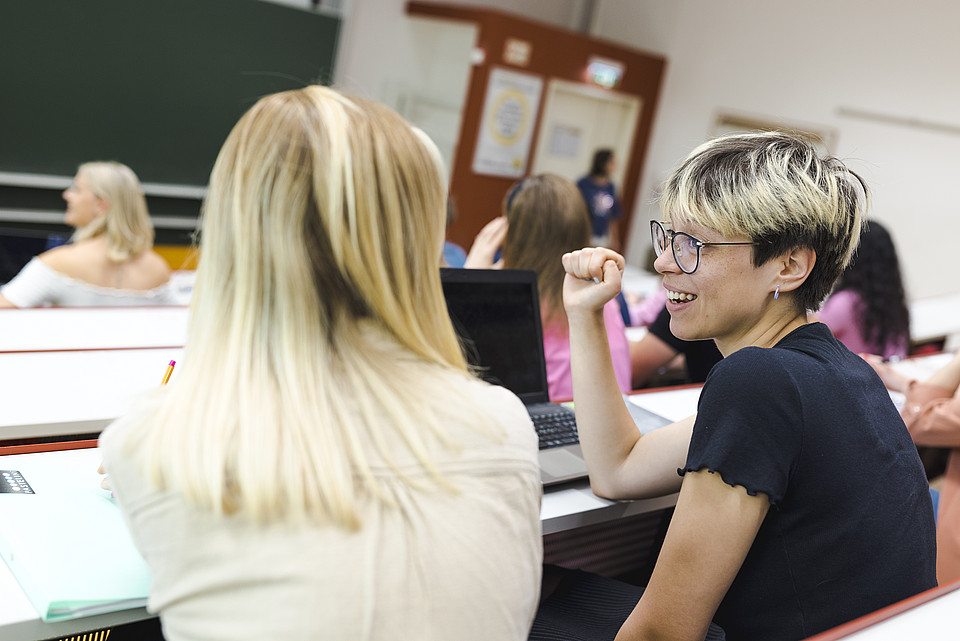 Zwei Studierende unterhalten sich im Seminarraum