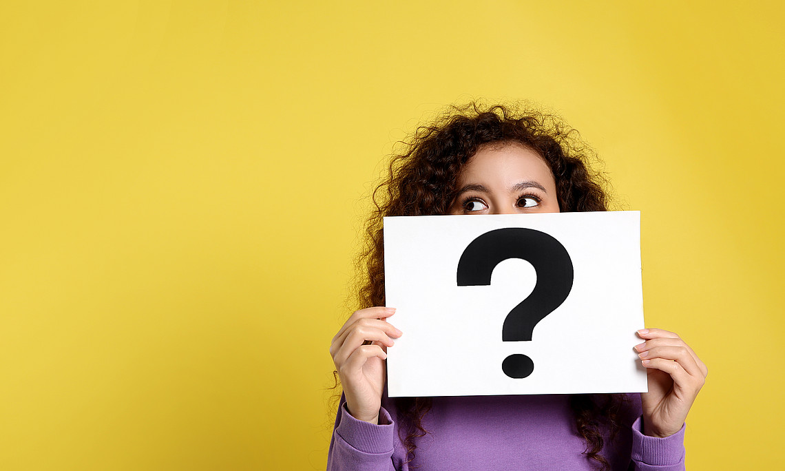 African-American woman with question mark sign on yellow background.