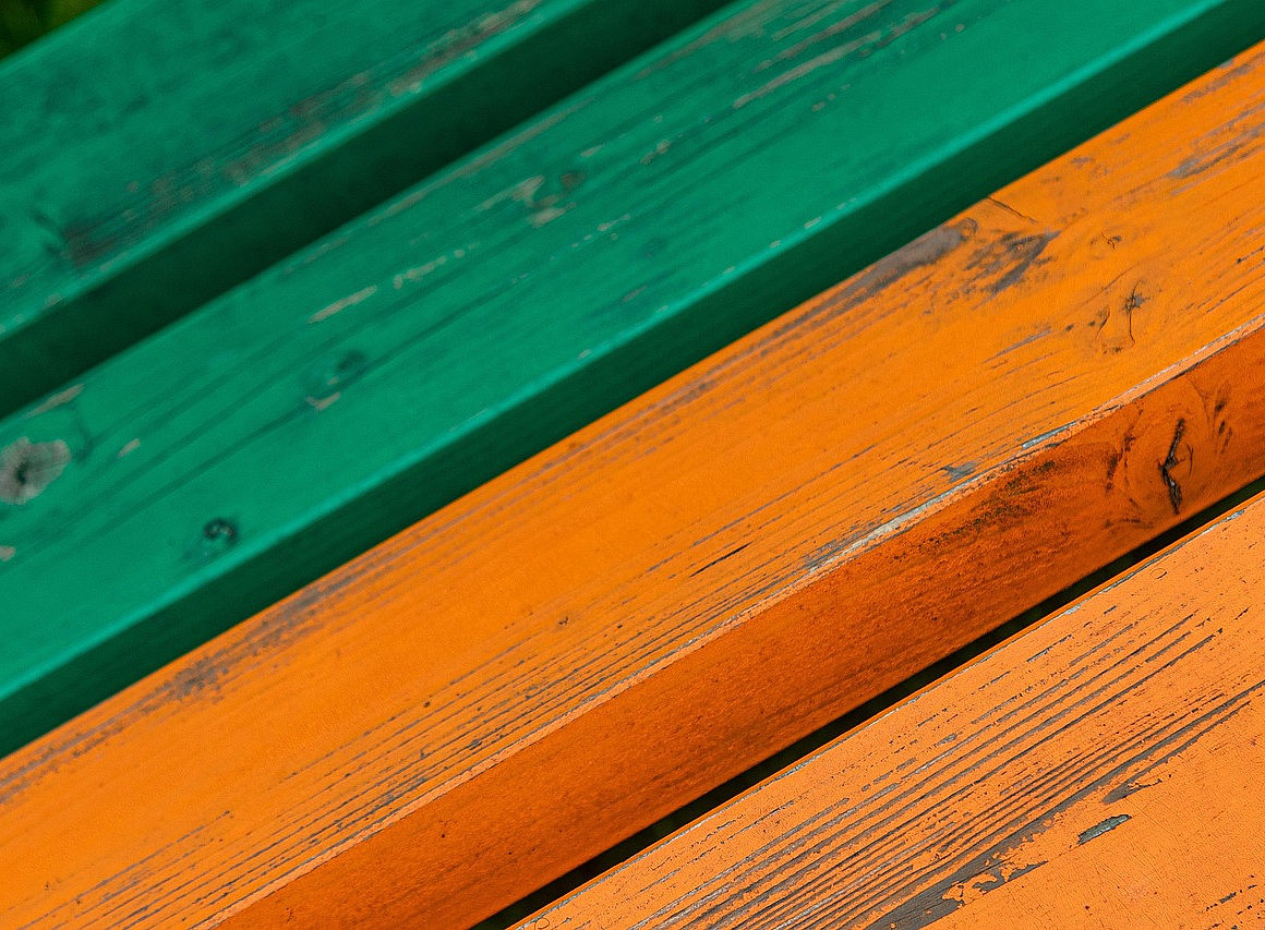 die Sitzfläche einer Bank mit grünem und dann orangenen Holz wird gezeigt ©Pixabay