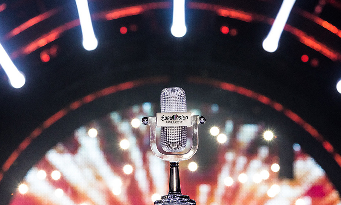 Die Trophäe des Eurovision Song Contest, ein gläsernes Mikrofon, im Hintergrund die Scheinwerfer der Bühne.