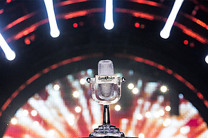 Die Trophäe des Eurovision Song Contest, ein gläsernes Mikrofon, im Hintergrund die Scheinwerfer der Bühne.