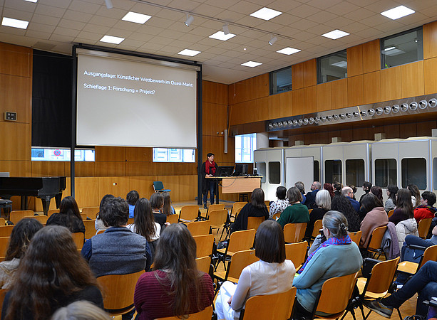 eine Frau steht in einem Hörsaal auf einem Podium und hält einen Vortrag, im Publikum sitzen viele Menschen und hören zu ©Uni Graz/Braunegger