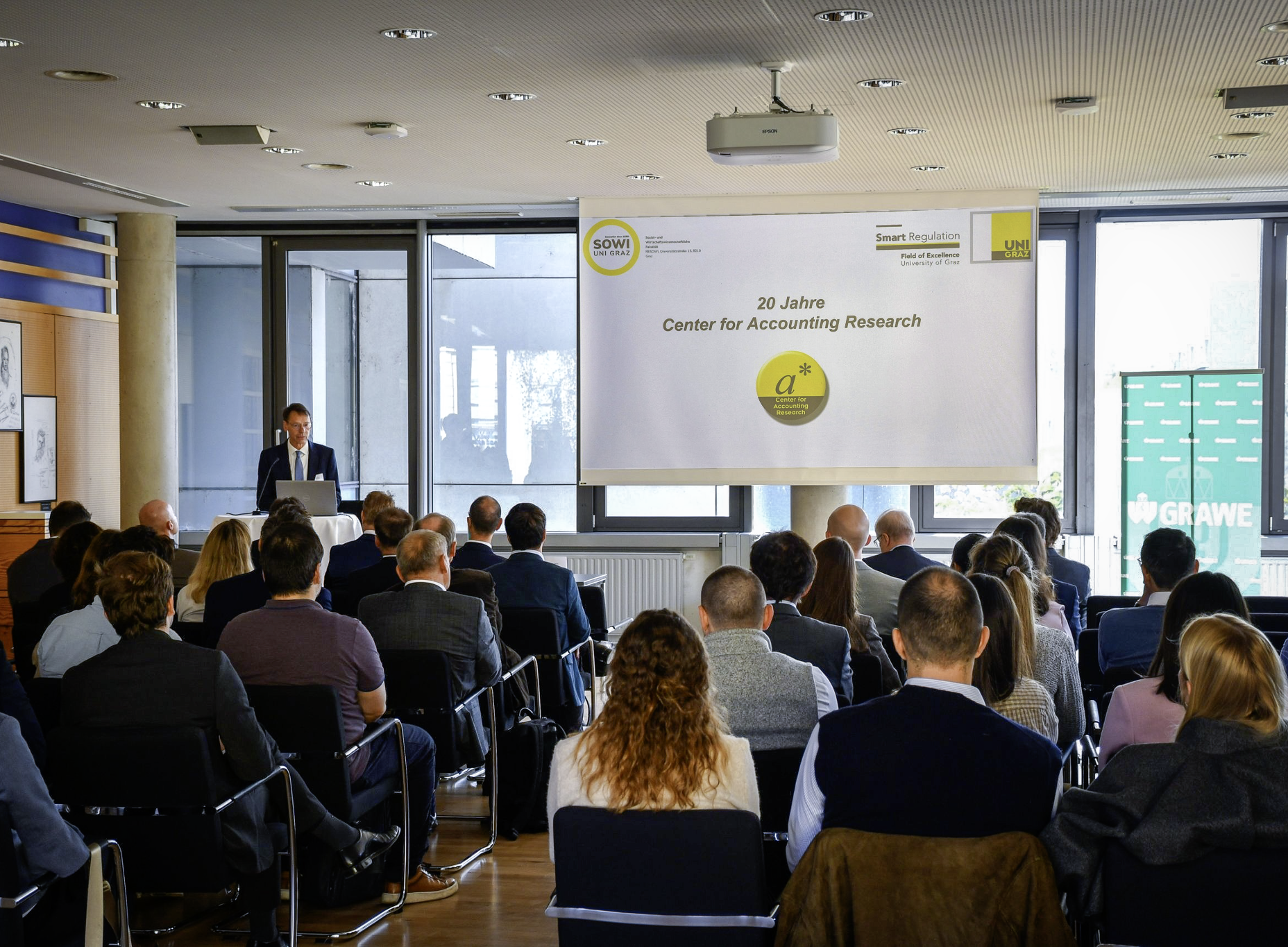 Blick aus dem Publikum auf einen Vortrag im Hörsaal. Auf der Leinwand steht „20 Jahre Center for Accounting Research“. ©SOWI/Habijanic