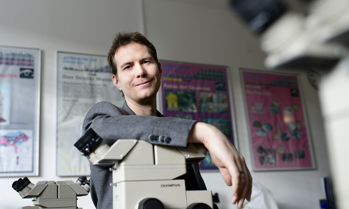 Earth scientist Gerald Auer leans over a microscope.