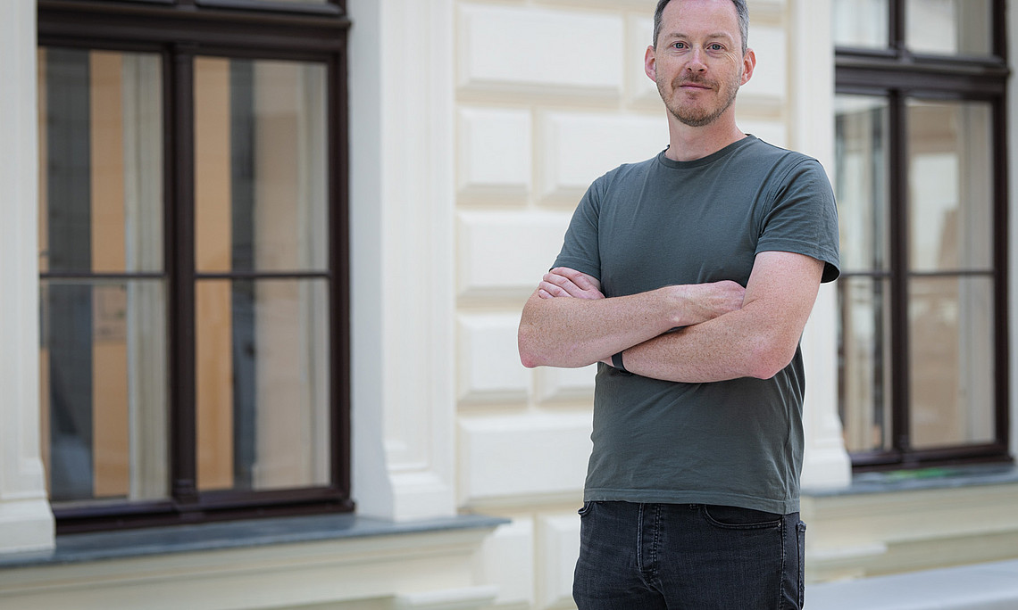 A man in a T-shirt, with his arms crossed