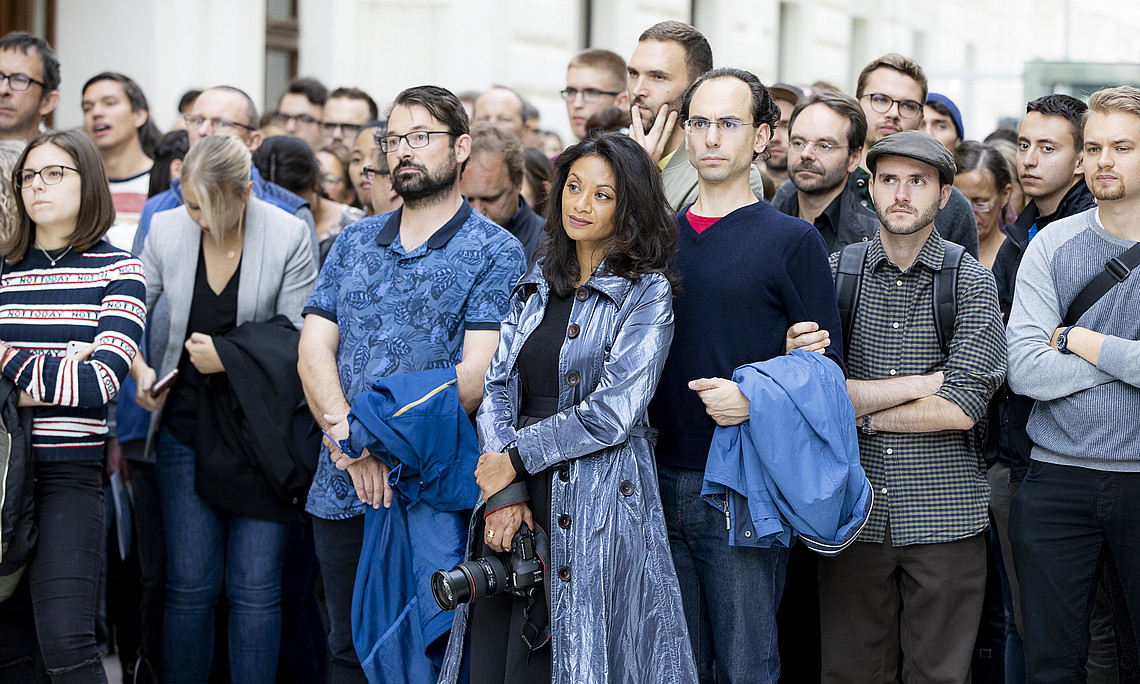 Eine Gruppe von Personen die versammelt in eine Richtung schauen und zuhören, was gesagt wird.
