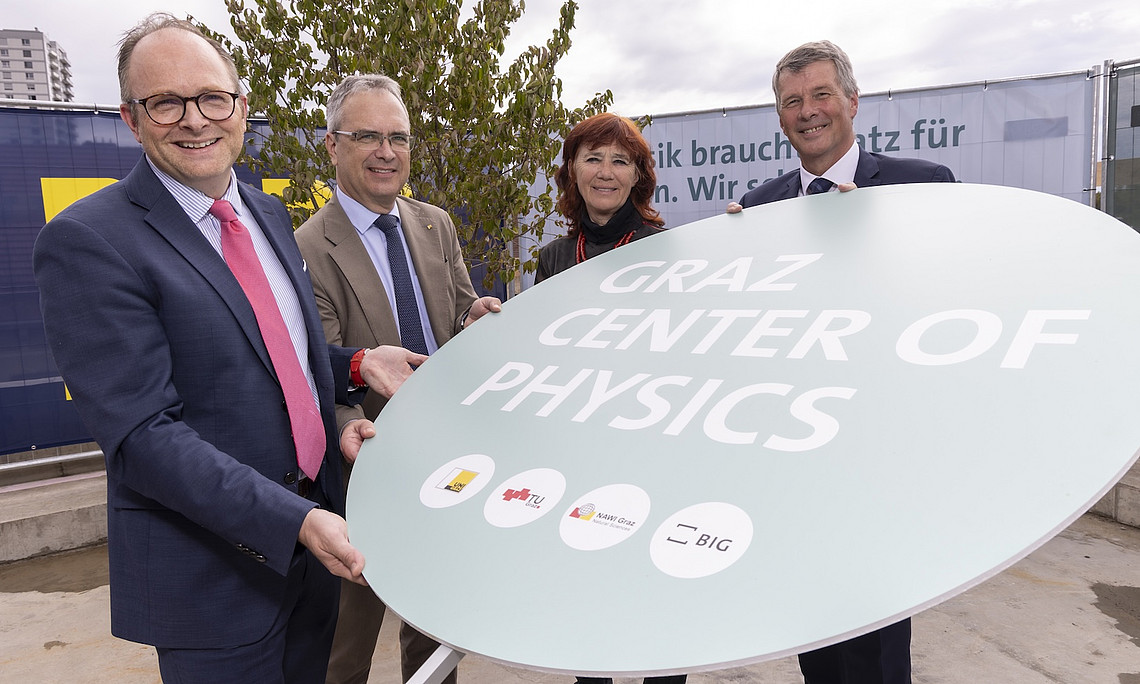 Drei Männer und eine Frau halten ein Schild 