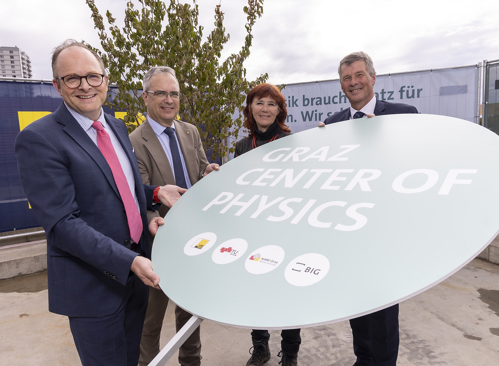 Drei Männer und eine Frau halten ein Schild 